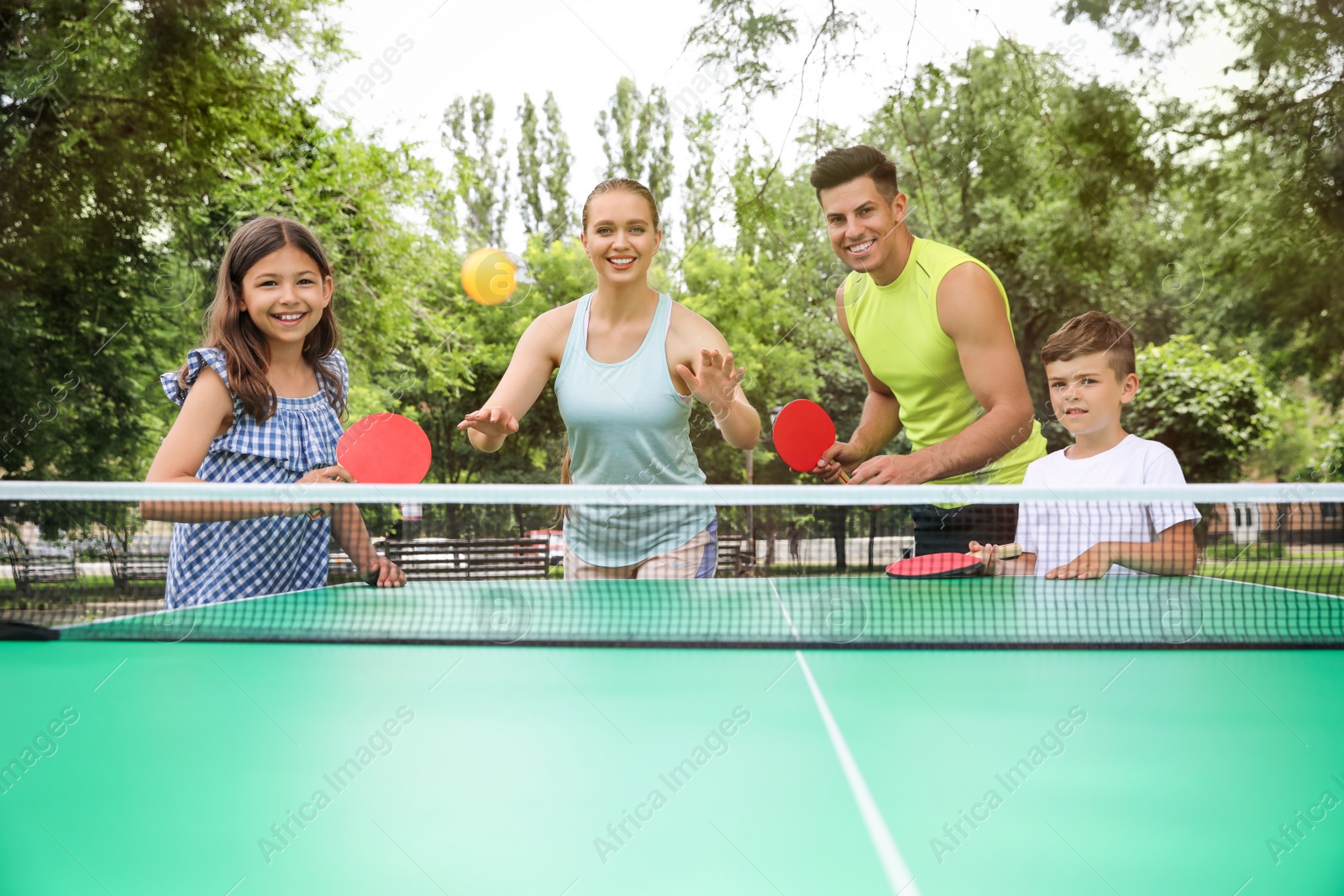 Photo of Happy family playing ping pong in park