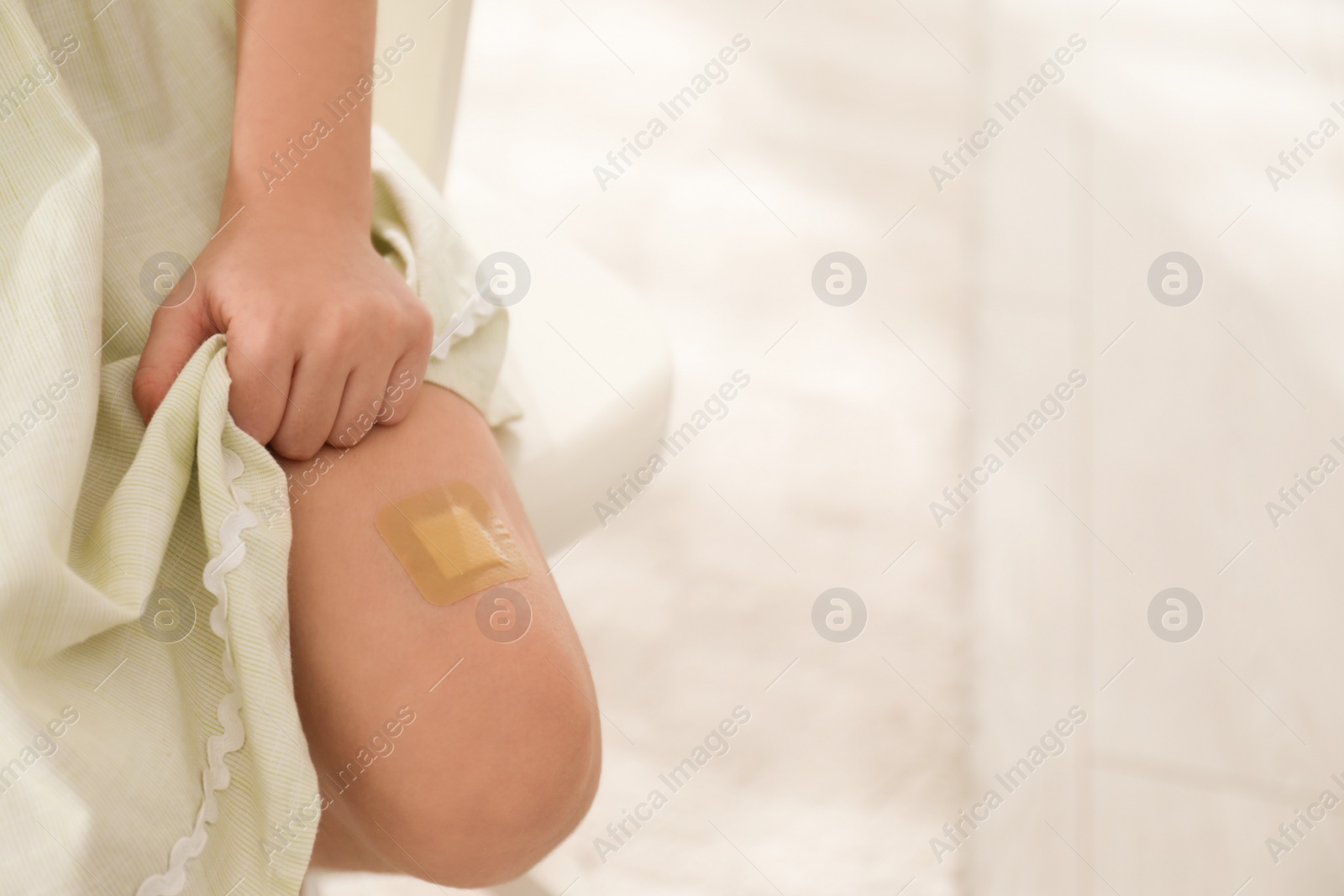 Photo of Girl with sticking plaster on leg indoors, closeup