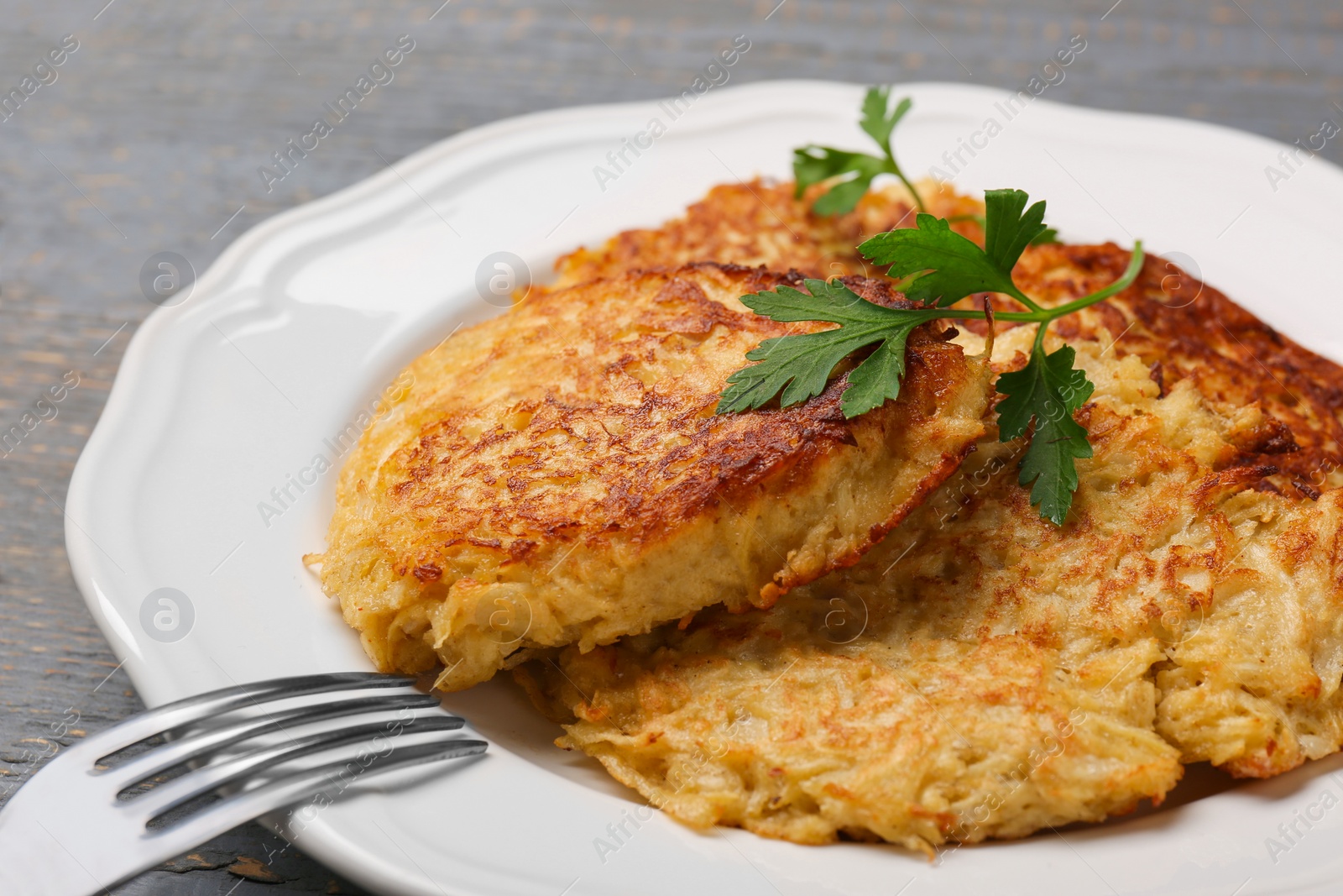 Photo of Tasty parsnip cutlets with parsley on grey wooden table, closeup