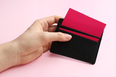 Woman holding business card holder with colorful cards on pink background, closeup