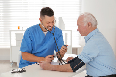 Photo of Doctor measuring blood pressure of senior patient in office