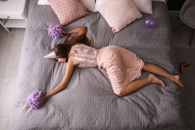 Photo of Exhausted woman in festive outfit sleeping on bed at home after party, above view