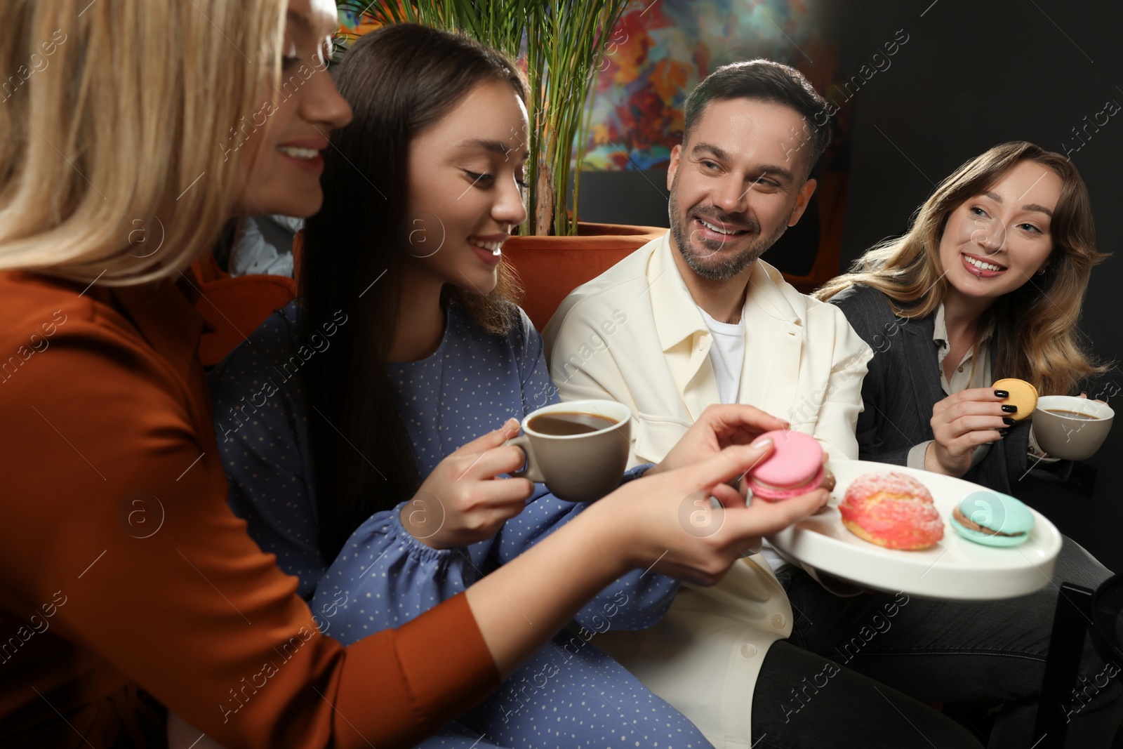 Photo of People with coffee and macarons spending time together in cafe