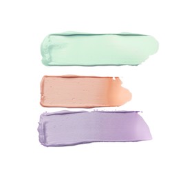 Photo of Strokes of pink, green and purple color correcting concealers on white background, top view