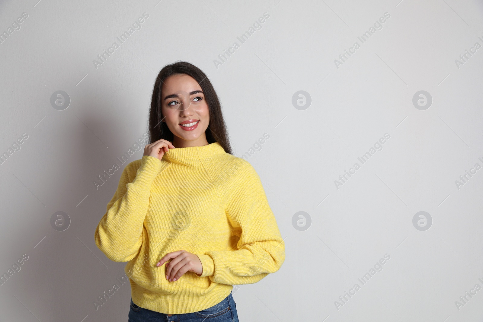 Photo of Beautiful young woman wearing yellow warm sweater on white background. Space for text