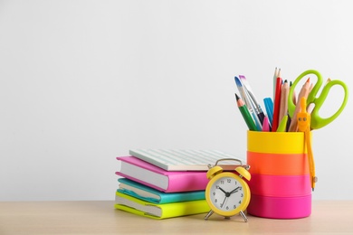 Photo of Different school stationery and alarm clock on table against white background, space for text. Back to school