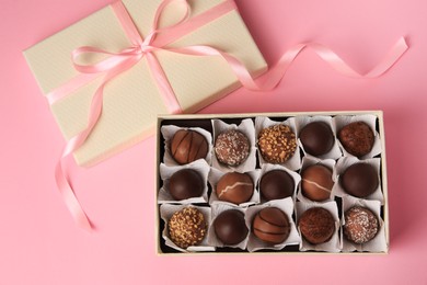 Box of delicious chocolate candies on pink background, flat lay