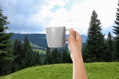 Image of Closeness to nature. Woman holding cup in mountains, closeup