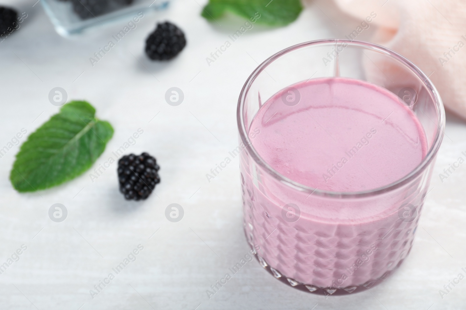 Photo of Glass with tasty blackberry yogurt smoothie on table