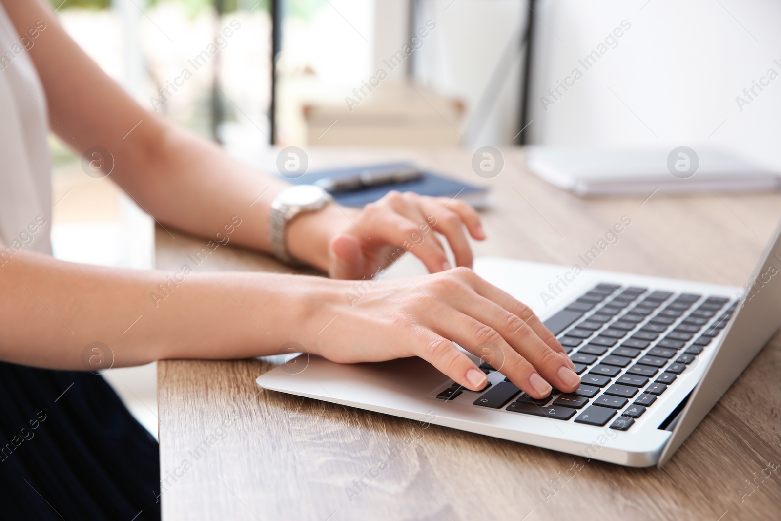 Photo of Young businesswoman using laptop at table in office