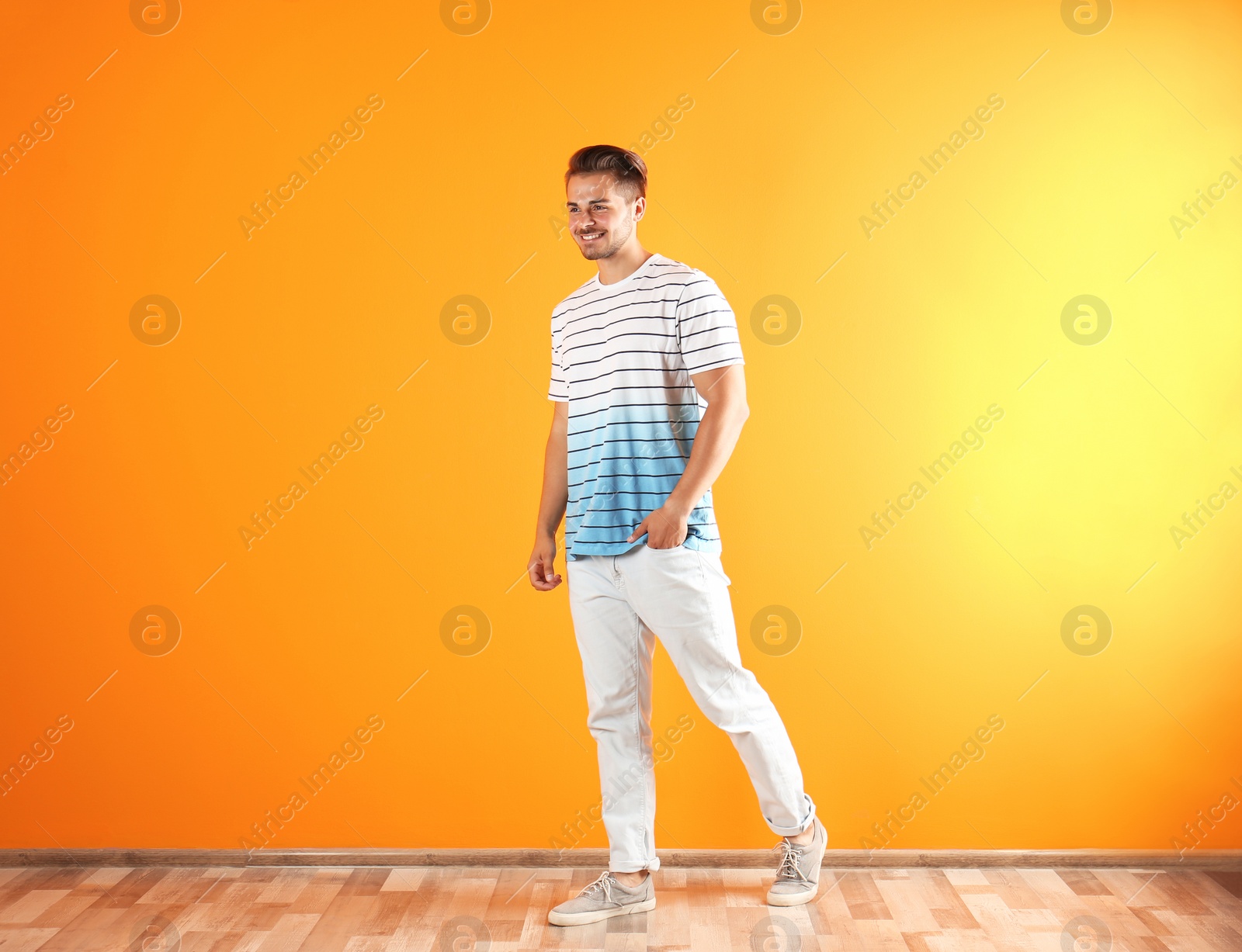 Photo of Young man in stylish jeans near color wall