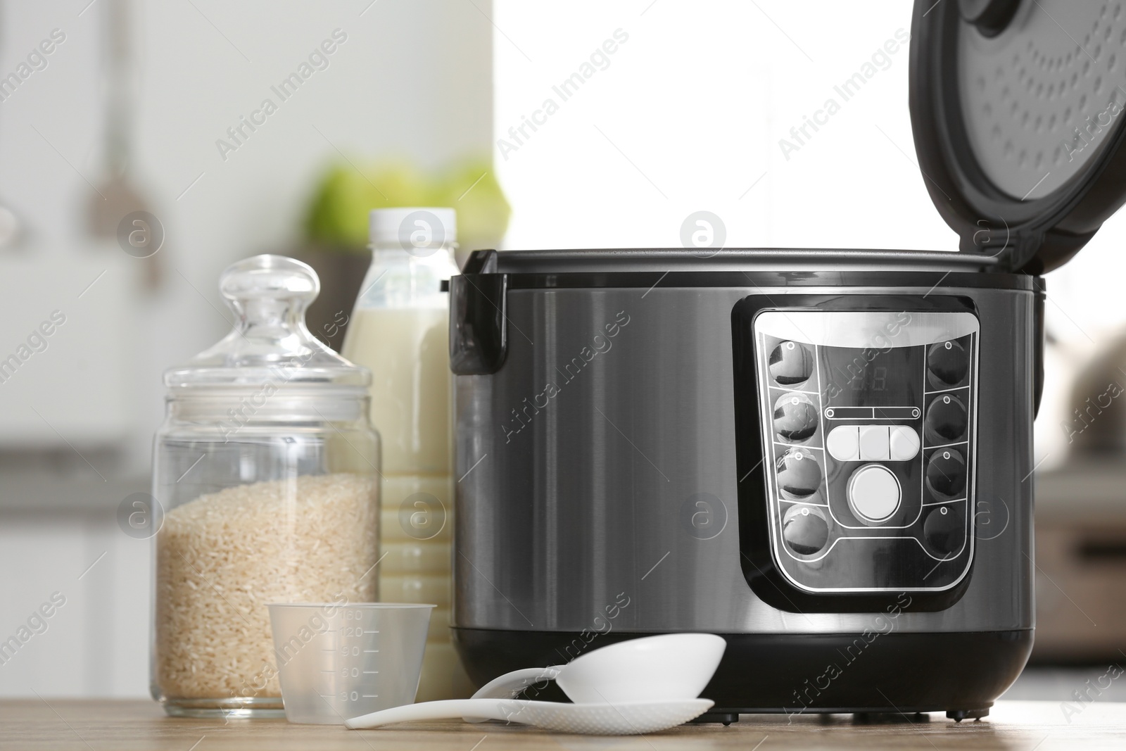 Photo of Modern electric multi cooker, rice and milk on table in kitchen