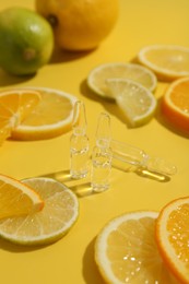 Photo of Skincare ampoules with vitamin C and citrus slices on yellow background