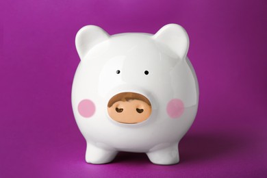 Photo of Ceramic piggy bank on purple background. Financial savings