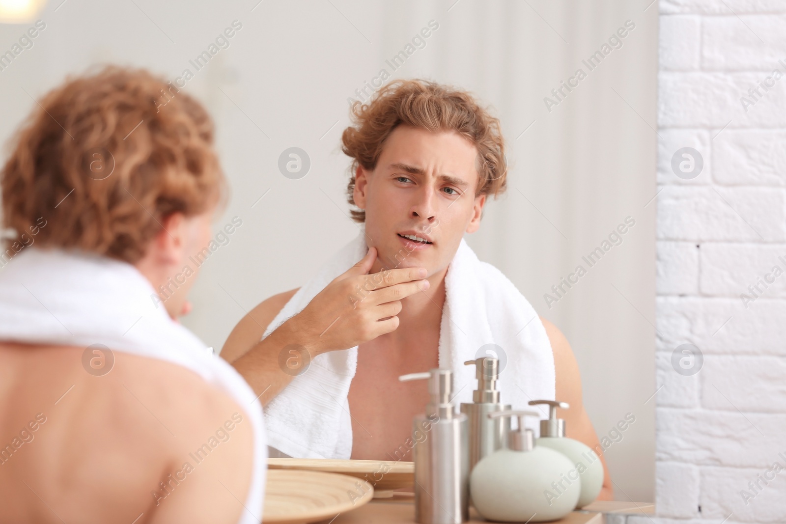 Photo of Young man looking in mirror after shaving at home