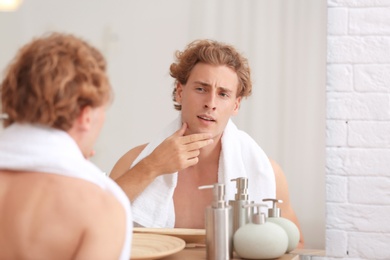 Photo of Young man looking in mirror after shaving at home