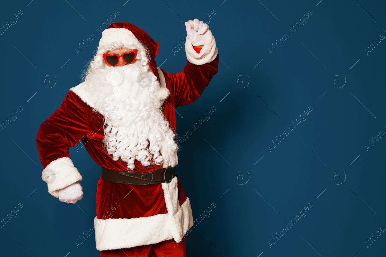 Photo of Authentic Santa Claus wearing sunglasses on blue background. Space for text