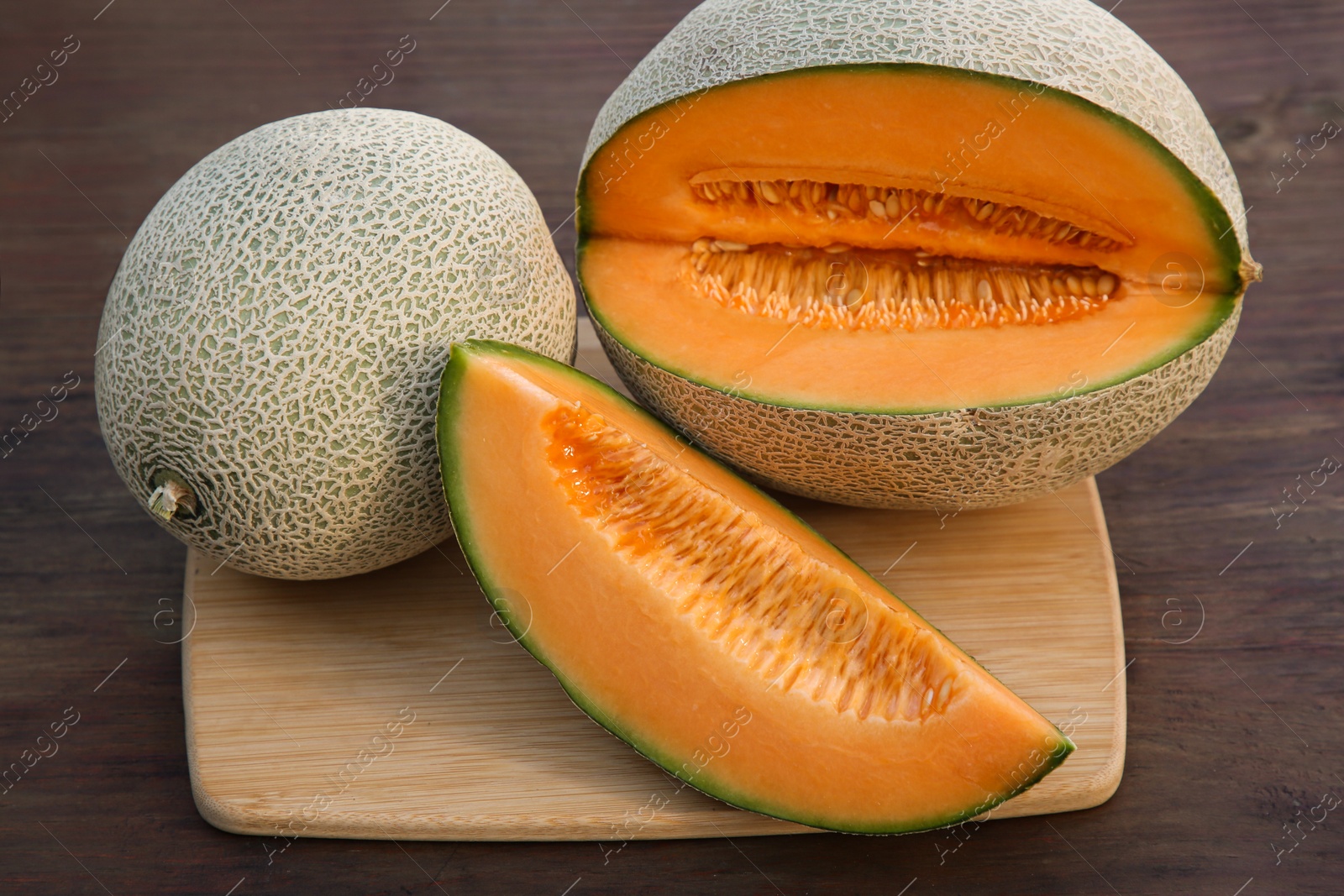 Photo of Whole and cut delicious ripe melons on wooden table
