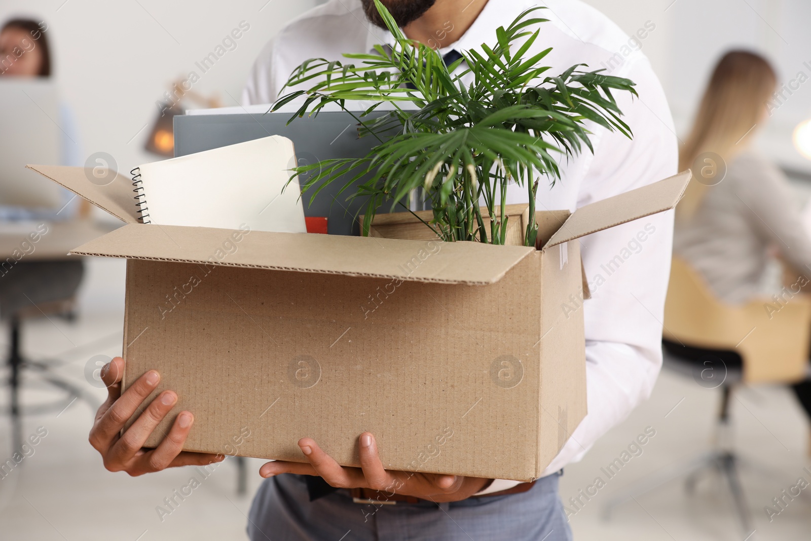 Photo of Unemployment problem. Man with box of personal belongings in office, closeup