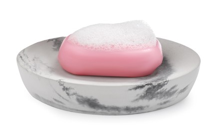 Soap bar with fluffy foam in holder on white background