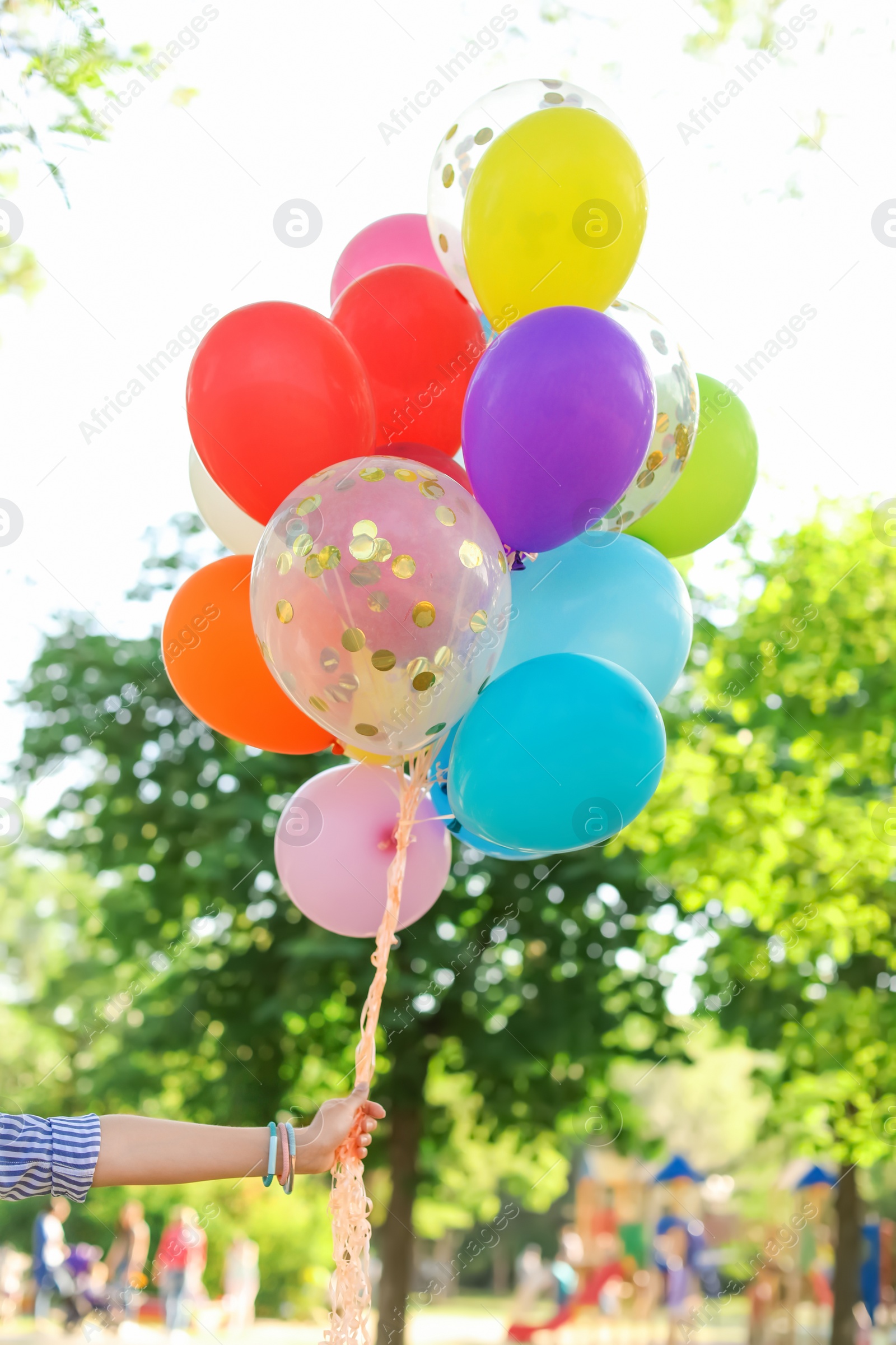 Photo of Young woman with colorful balloons outdoors on sunny day