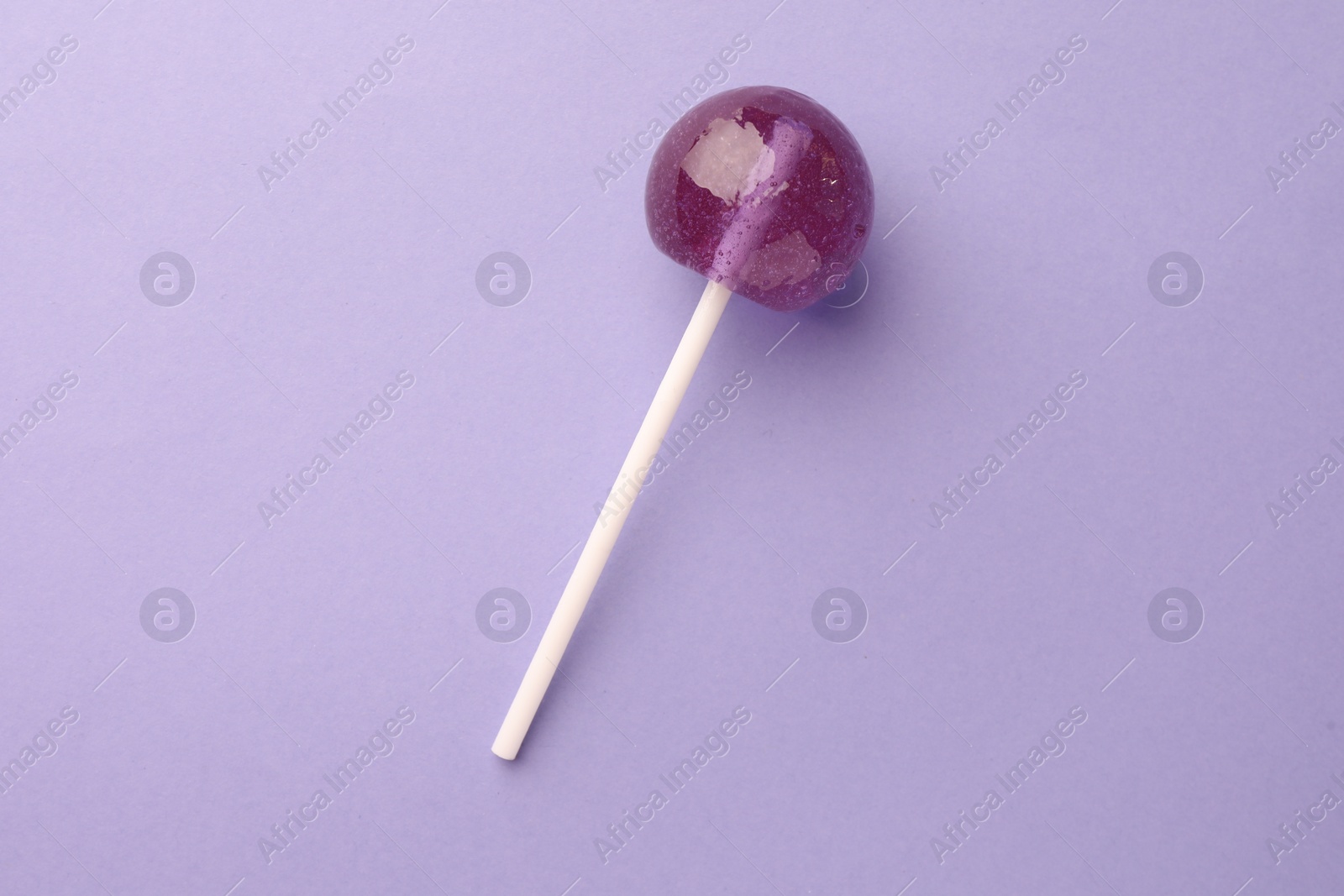 Photo of Tasty lollipop on violet background, top view