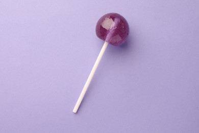 Photo of Tasty lollipop on violet background, top view