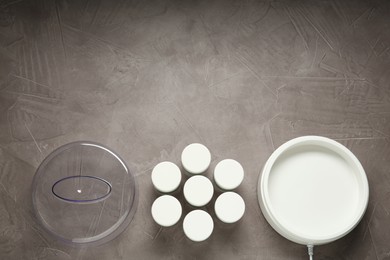 Modern yogurt maker with jars on grey table, flat lay. Space for text