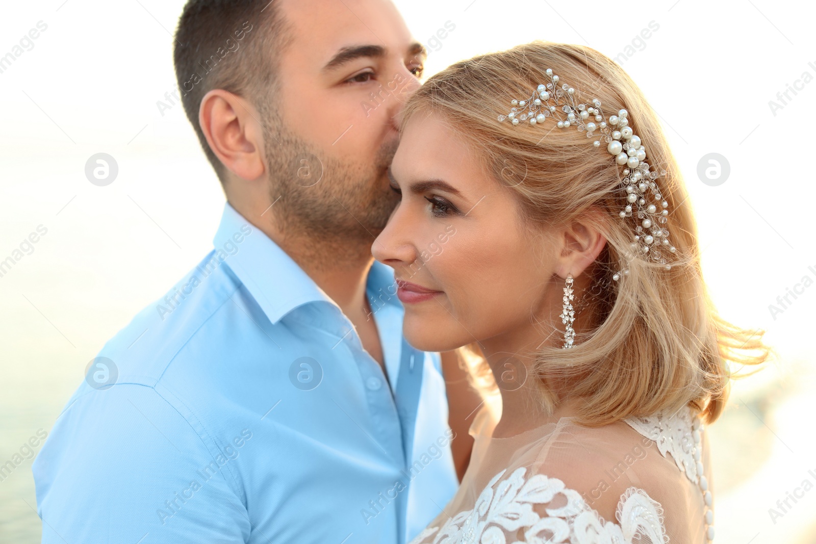 Photo of Wedding couple. Groom kissing bride on beach