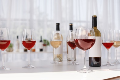 Photo of Glasses and bottles with delicious wine on table indoors