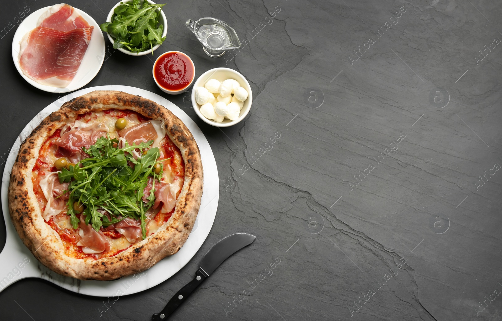 Photo of Tasty pizza with meat and arugula on black table, flat lay. Space for text