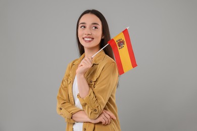 Photo of Young woman holding flag of Spain on light grey background