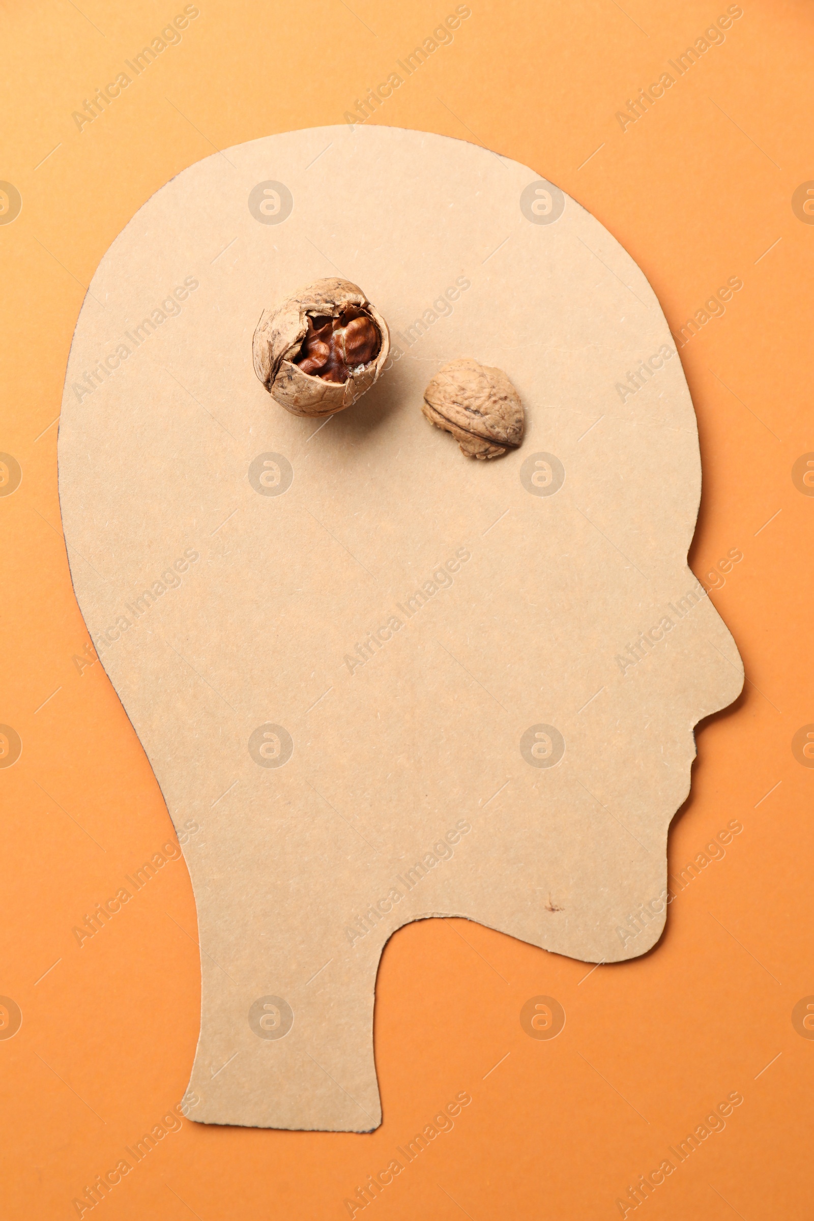 Photo of Amnesia problem. Paper cutout of human head and broken walnut on orange background, top view