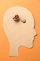 Photo of Amnesia problem. Paper cutout of human head and broken walnut on orange background, top view