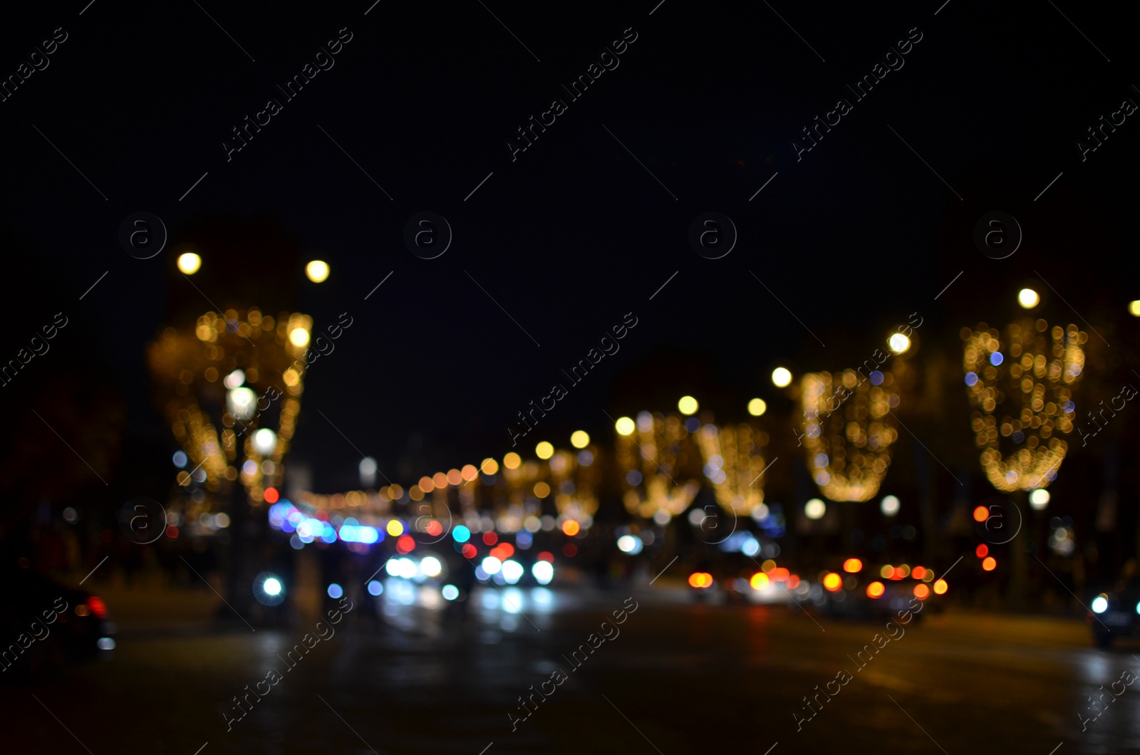 Photo of Blurred view of street with beautiful lights on trees and cars at night. Bokeh effect