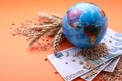 Photo of Import and export concept. Globe, ears of wheat and banknotes on orange background