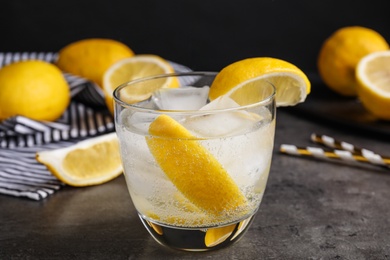 Photo of Soda water with lemon slices and ice cubes on grey table