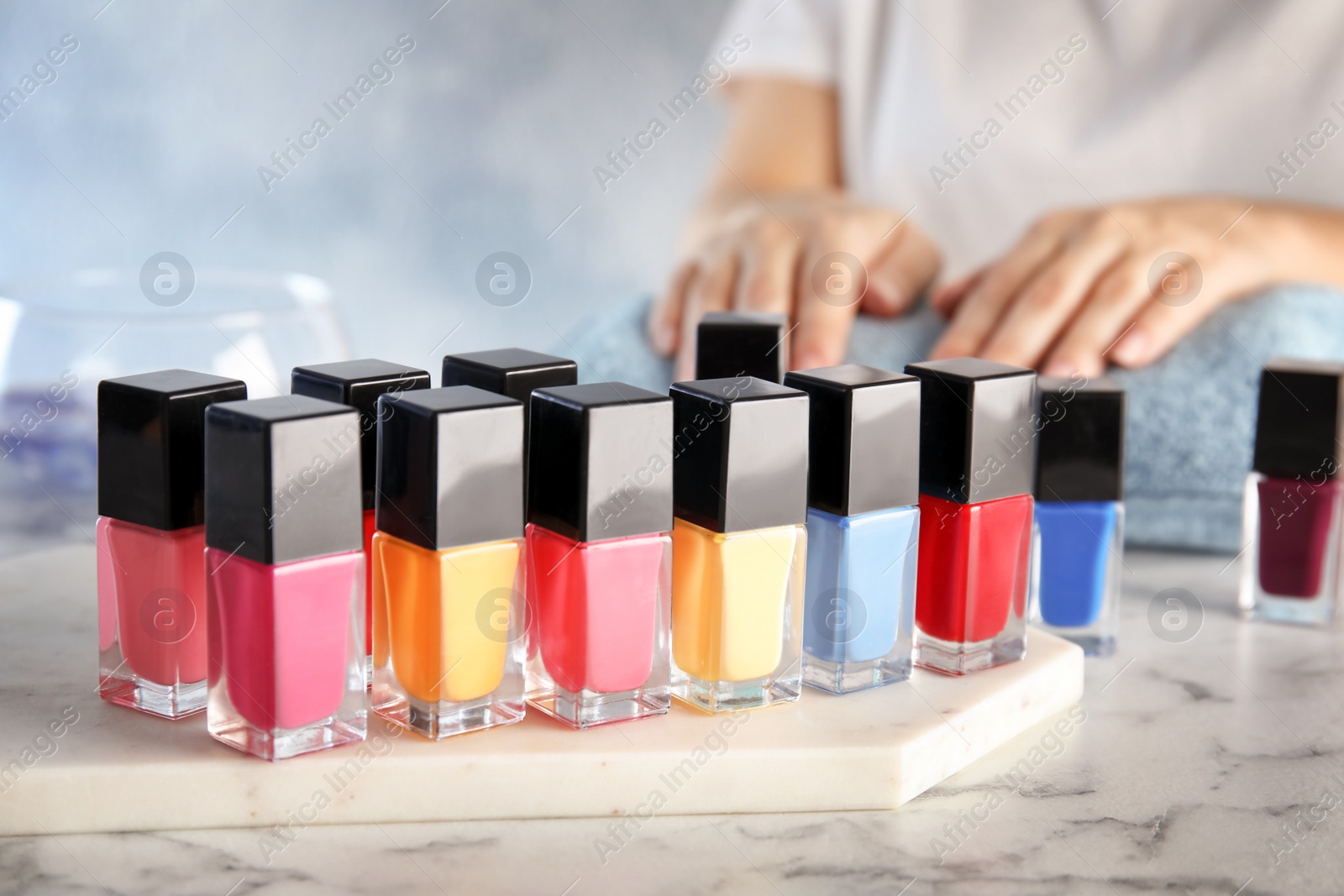 Photo of Bottles of bright nail polish and blurred woman on background