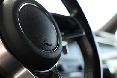 Photo of Steering wheel inside of black modern car, closeup