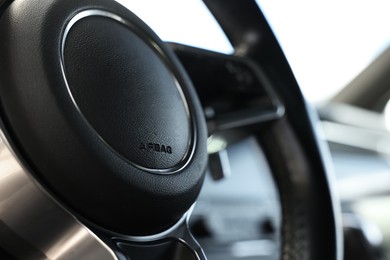 Steering wheel inside of black modern car, closeup