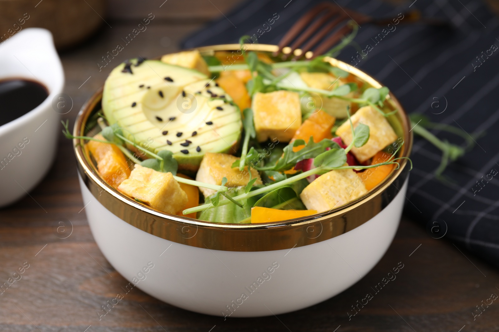 Photo of Delicious salad with tofu and vegetables on wooden table, closeup