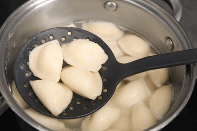 Photo of Dumplings (varenyky) with cottage cheese on skimmer over pot, closeup