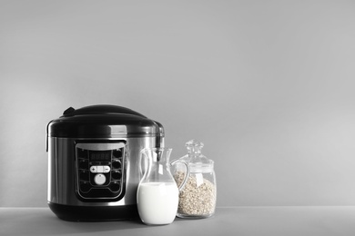 Photo of Modern multi cooker and products on table against grey background. Space for text