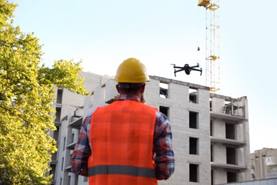 Photo of Builder operating drone with remote control at construction site. Aerial photography