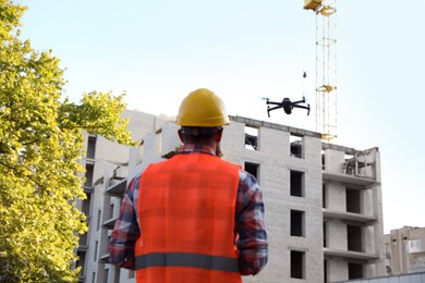 Builder operating drone with remote control at construction site. Aerial photography