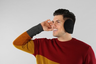 Photo of Man wearing stylish earmuffs on light background