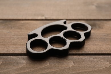 Photo of Black brass knuckles on wooden background, closeup