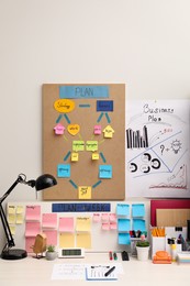Photo of Business process planning and optimization. Workplace with lamp, colorful paper notes and other stationery on white wooden table