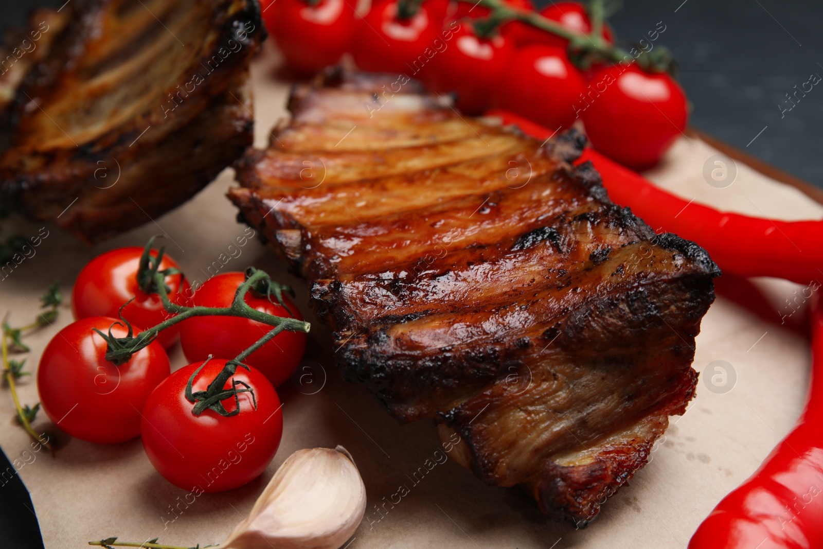 Photo of Tasty grilled ribs with tomatoes and peppers on table, closeup