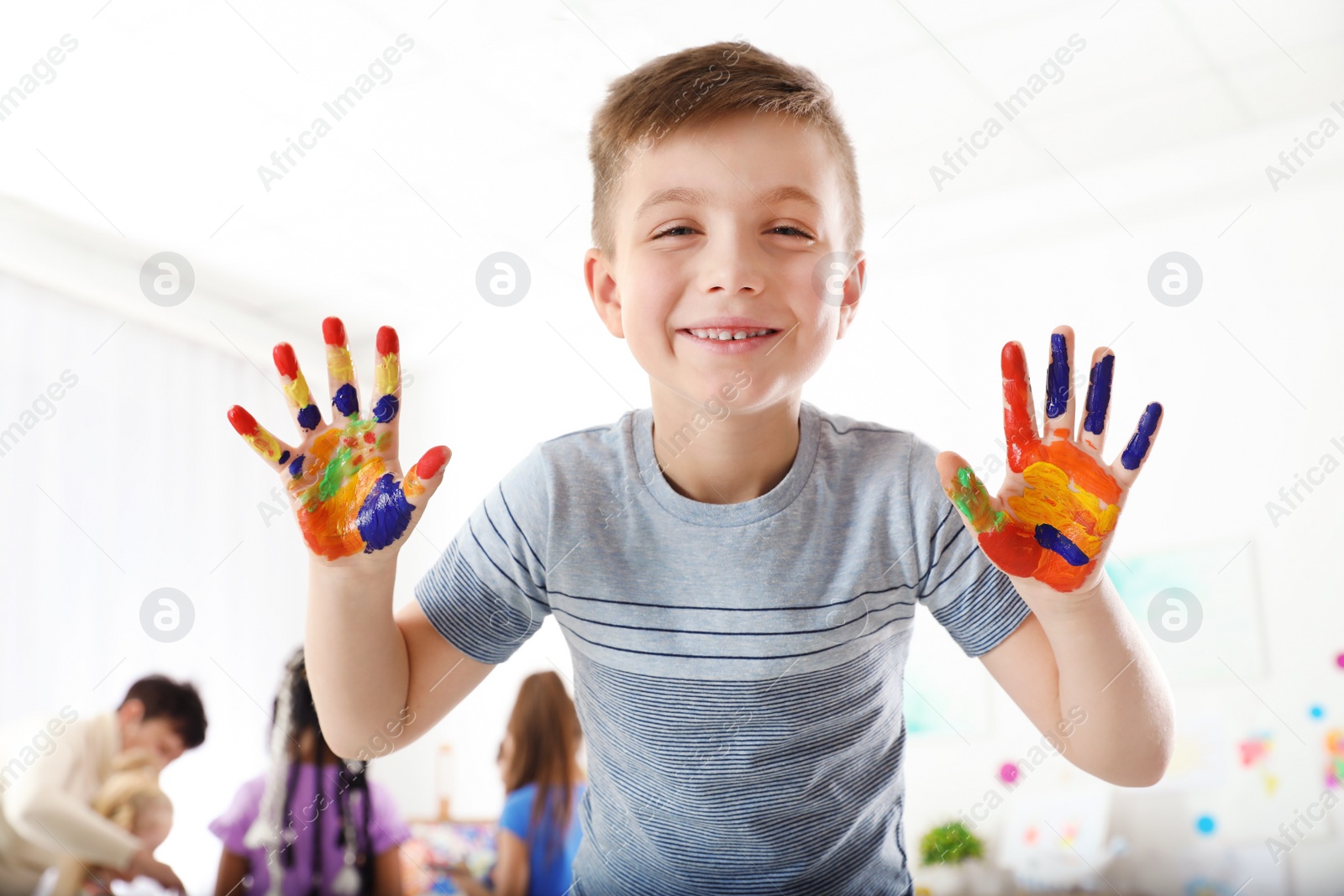 Photo of Cute little child showing painted hands at lesson indoors